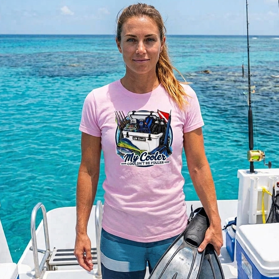 A woman stands on a boat holding flip-flops, wearing a light pink graphic t-shirt that reads 'My Cooler Florida'. The background features bright turquoise ocean water and fishing gear.